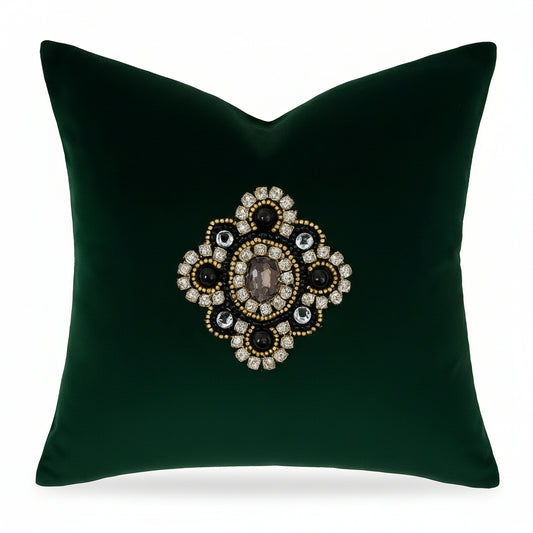 Green cushion cover with a decorative brooch-like embellishment on a white background